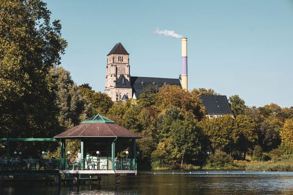 Schöner Blick auf die Lutherische Kirche und den Park in Chemnitz, Deutschland, mit einem Schornstein im Hintergrund.
