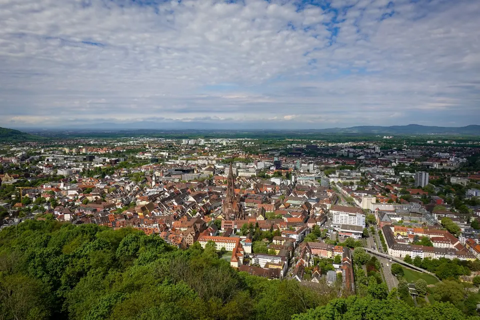 Panoramische Luftaufnahme von Freiburg, die seine ikonische Kathedrale und die üppige Vegetation zeigt.
