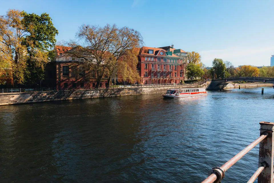 Ausflugsbootfahrt auf der Spree in Berlin an einem sonnigen Tag mit historischen Gebäuden und blauem Himmel.