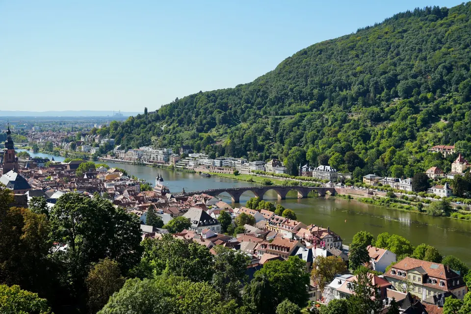 Luftaufnahme der Heidelberger Altstadt mit dem Neckar und der historischen Brücke unter einem klaren blauen Himmel.