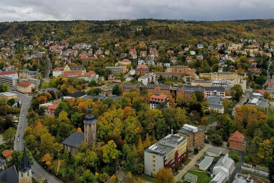 Luftaufnahme von Jena, Deutschland, die die bunten Herbstblätter und die historische Architektur zeigt.