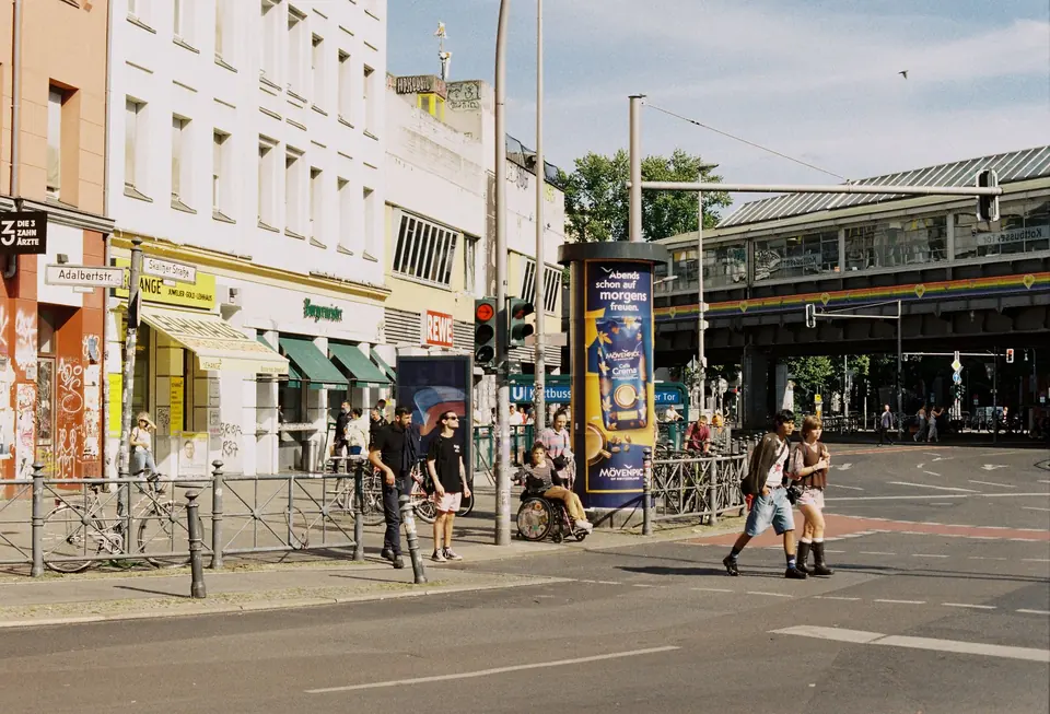 Menschen, die die Straße in Kreuzberg, Berlin überqueren und das städtische Leben sowie die lebendige Straßenkultur zeigen.