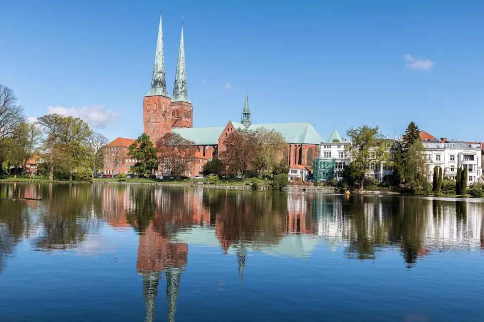 Schöne Reflexion des Lübecker Doms und historischer Gebäude am Fluss im Frühling.