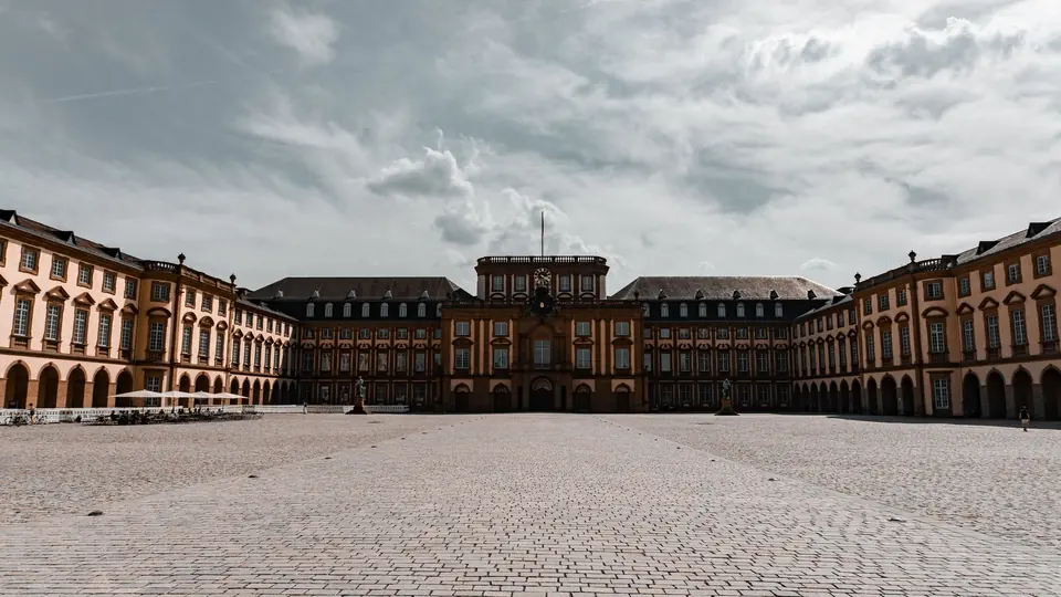 Eine malerische Innenhofansicht des Mannheimer Schlosses in Deutschland, das barocke Architektur unter einem bewölkten Himmel zeigt.