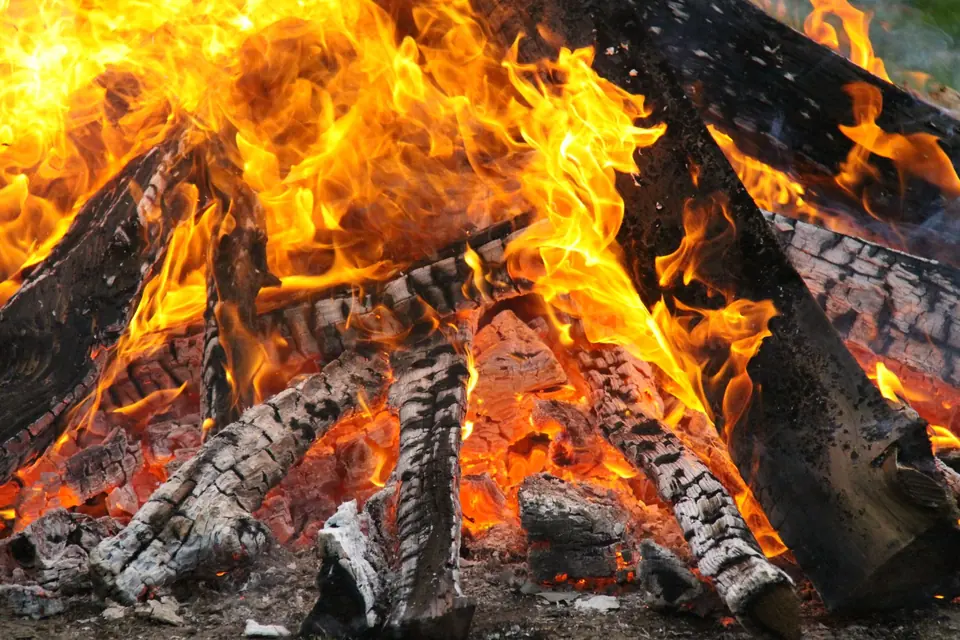 Eine fesselnde Nahaufnahme eines lodernden Lagerfeuers mit lebendigen Flammen und Glut, die Wärme und Licht erzeugen.